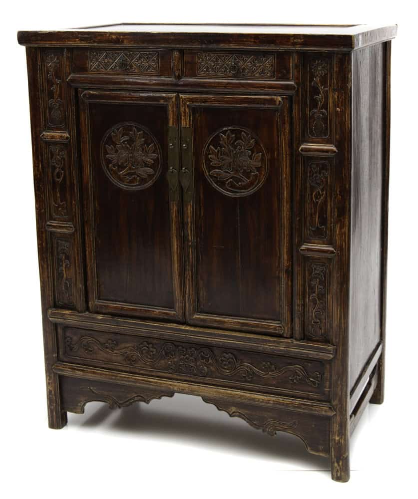 Angled view of the 19th century Chinese cabinet with peony medallion carvings and intricate detailing.