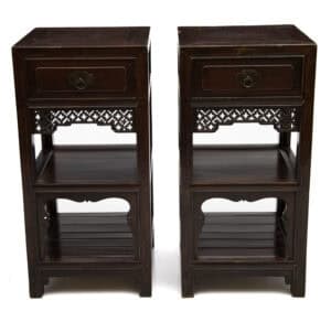 Front view of a pair of 19th century Chinese elmwood tea stands with carved apron and open shelves.
