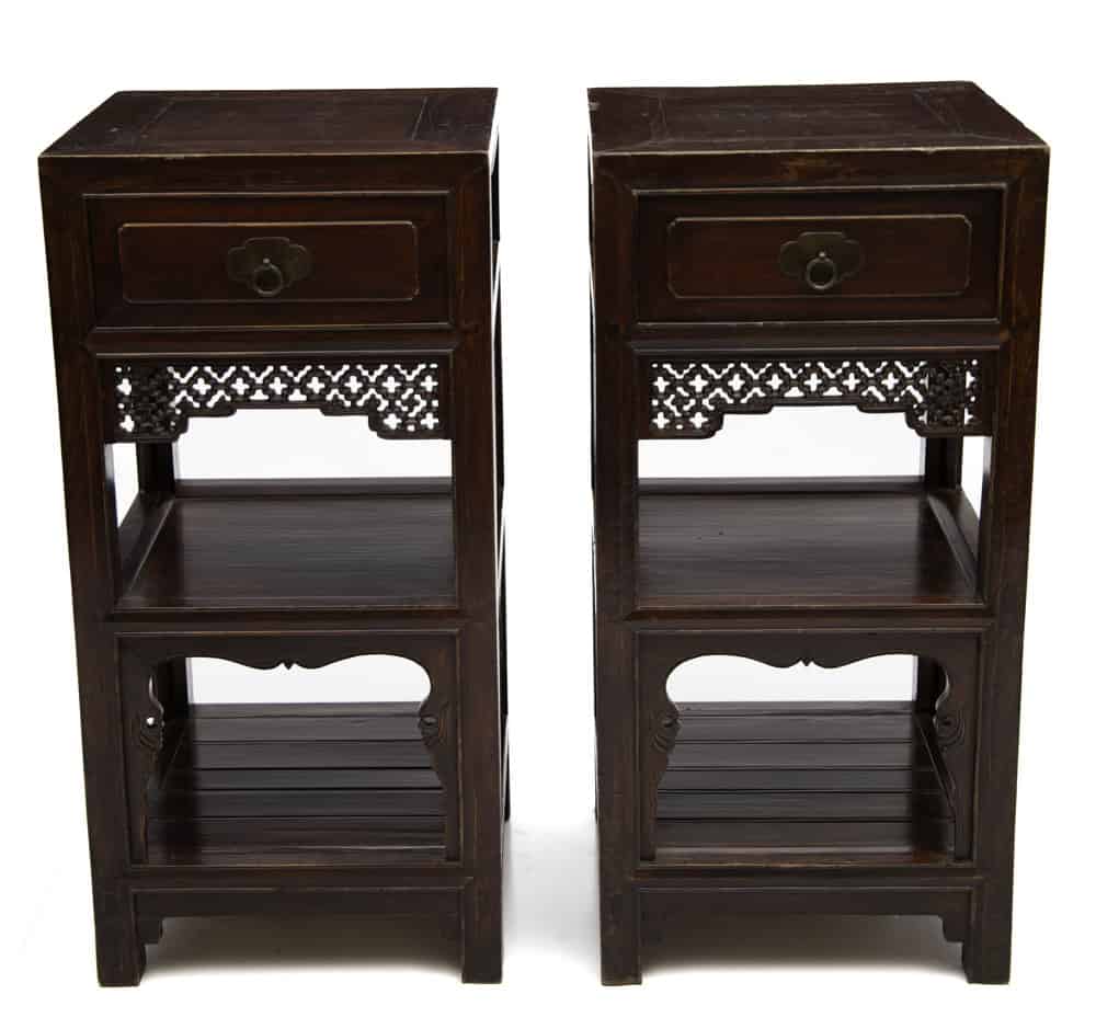 Front view of a pair of 19th century Chinese elmwood tea stands with carved apron and open shelves.